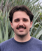 A picture of Charles Heyder in front of palm fronds
