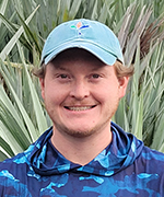 A picture of Myles Domohowski in front of palm fronds